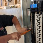 Technician working on an electrical panel, showcasing services by Cardinal Heating & Air Conditioning.