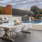 Outdoor dining area with swimming pool and barbecue grill, by Cardinal Heating, Cooling, Plumbing & Electric.