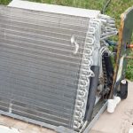 Air conditioning unit on concrete base with metal coils by Cardinal Heating, Cooling, Plumbing & Electric.