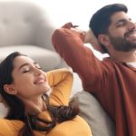 A man and woman relaxed on a couch, representing comfort and enjoyment while discussing HVAC services in Sun Prairie, WI.