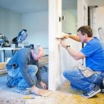 Two men adjusting a door frame in a construction project by Cardinal Heating, Cooling, Plumbing & Electric.