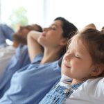 Three people, including a child, resting indoors, showcasing relaxation. Cardinal Heating & Air Conditioning.