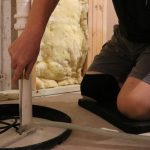 Person kneeling to install a pipe with tools for plumbing by Cardinal Heating, Cooling, Plumbing & Electric.