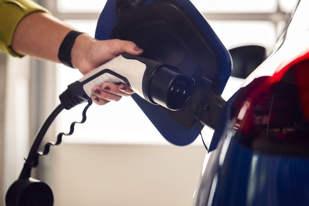 Person holding an electric vehicle charging handle, highlighting modern design for eco-friendly transportation.