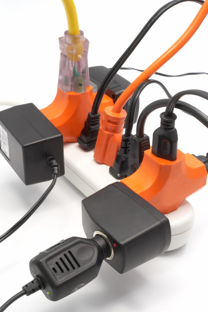 Extension cords and power strips connected, illustrating overloaded circuits and electrical safety risks in homes during the holiday season.