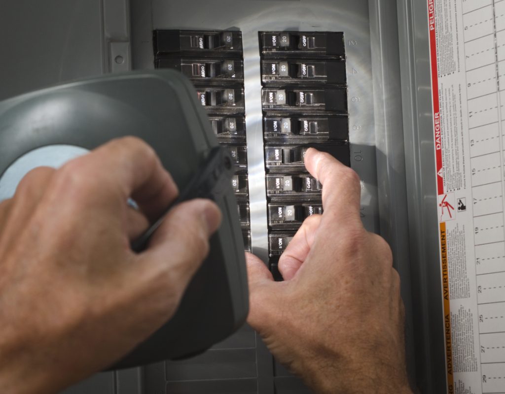 Person inspecting electrical panel with circuit breakers, highlighting the importance of electrical safety during the holiday season.